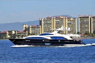 The Azimut 105 cruising past a row of apartment towers with mountains in the background