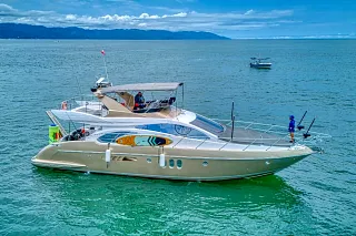 El Azimut 58 Fly anclado en agua turquesa de la bahía con montañas al fondo