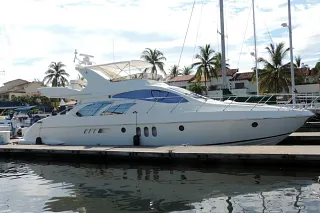 El Azimut 58 atracado en la marina con palmeras y mástiles de veleros al fondo