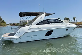 The Beneteau 35 with its black bimini on calm marina water under a clear blue sky