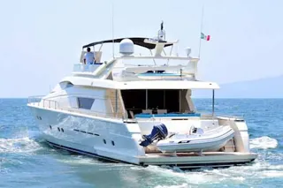 El Ferretti 80 navegando con su lancha auxiliar en la popa y montañas a lo lejos