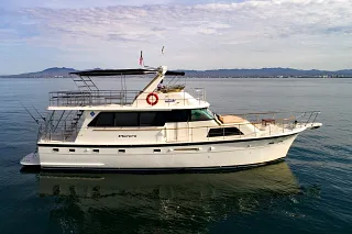 The Hatteras 58 flybridge yacht on calm water with mountains on the horizon