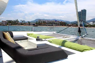 Foredeck lounge on the Lagoon 45 II with cushions and trampolines, facing the shoreline